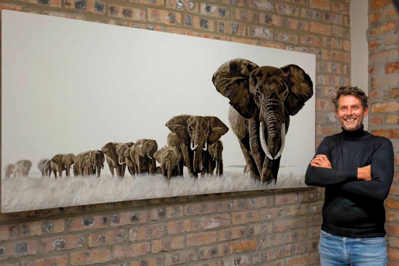 André Peypers standing beside his large-scale elephant herd painting
